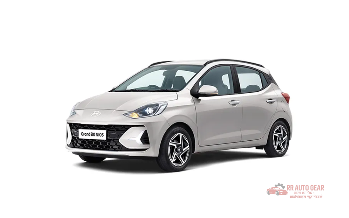 Front and side view of the 2025 Hyundai Grand i10 in red color, parked on an urban road showing its sleek design, alloy wheels, LED DRLs, and modern styling features.